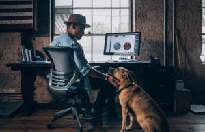 dog next to a man sitting at his desk